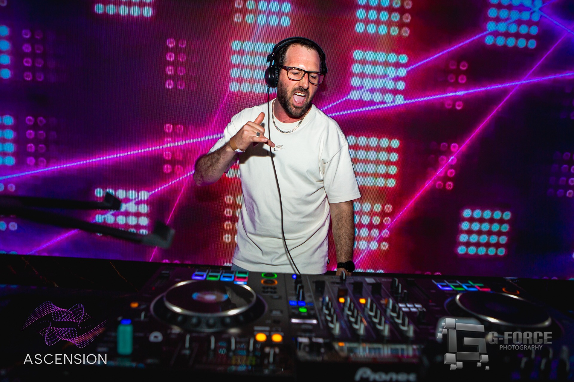 DJ performing behind Pioneer controller with pink and purple lasers