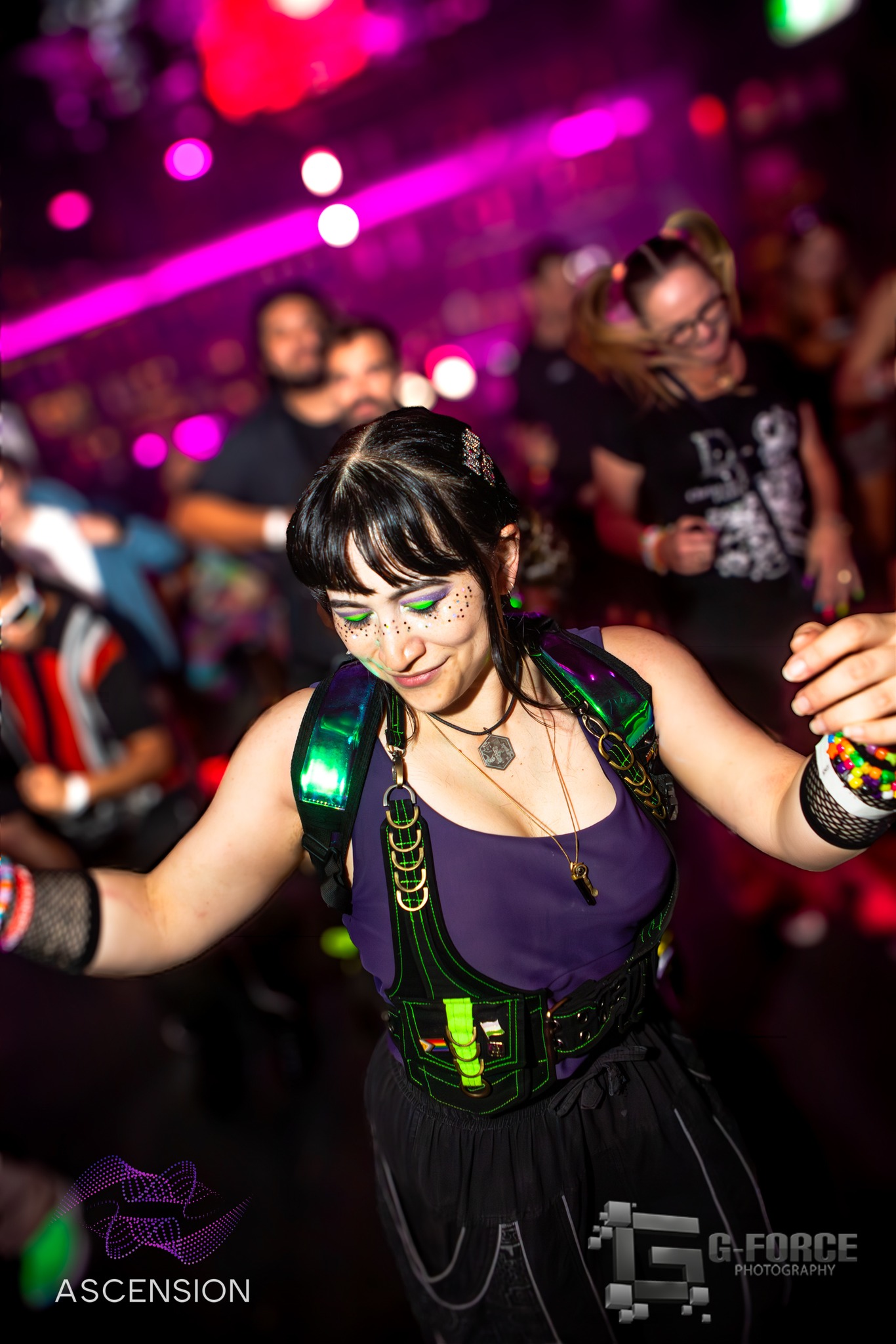 Festival-goer dancing in neon rave outfit under pink stage lights